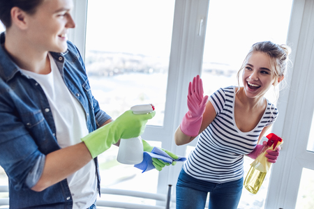 Young happy couple is having fun while doing cleaning at home.の写真素材