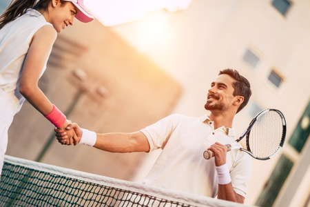 Young couple on tennis court. Handsome man and attractive woman are playing tennis. Handshaking.の写真素材