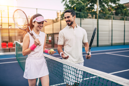 Young couple on tennis court. Handsome man and attractive woman are playing tennis.の写真素材
