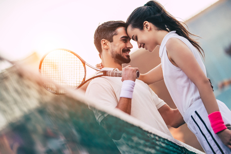Young couple on tennis court. Handsome man and attractive woman are playing tennis.の写真素材
