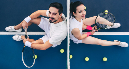 Top view of young couple is sitting on tennis court. Handsome man and attractive woman are playing tennis.の写真素材