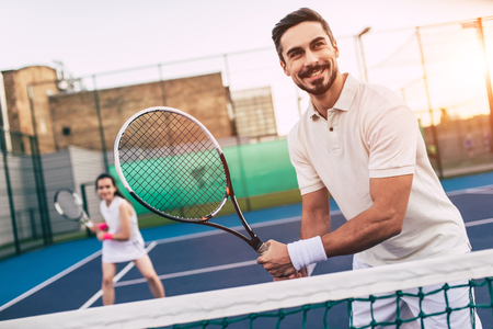 Young couple on tennis court. Handsome man and attractive woman are playing tennis.の写真素材
