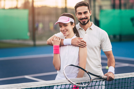 Young couple on tennis court. Handsome man and attractive woman are playing tennis.の写真素材