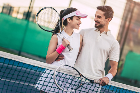 Young couple on tennis court. Handsome man and attractive woman are playing tennis.の写真素材
