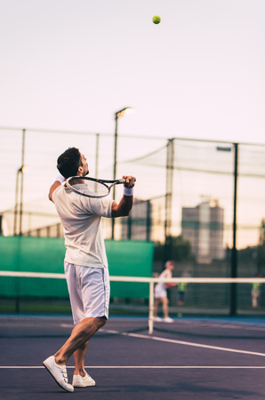 Young couple on tennis court. Handsome man and attractive woman are playing tennis.の写真素材