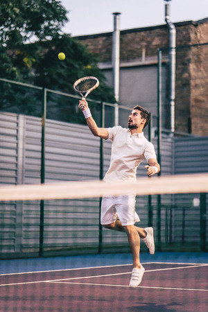 Handsome man on tennis court. Young male tennis player.の写真素材