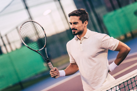 Handsome man on tennis court. Young tennis player. Backache.の写真素材