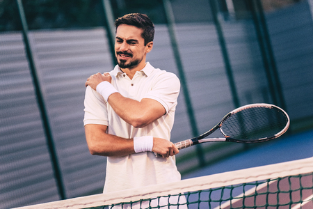 Handsome man on tennis court. Young tennis player. Shoulder pain