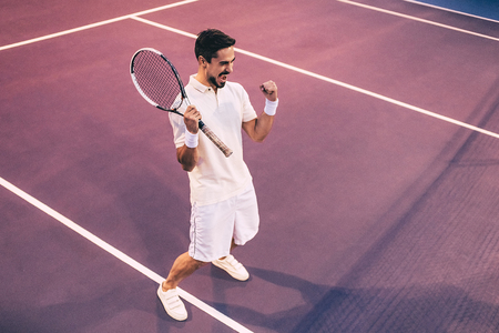 Handsome man on tennis court. Young male tennis player. Victory! Success!の写真素材