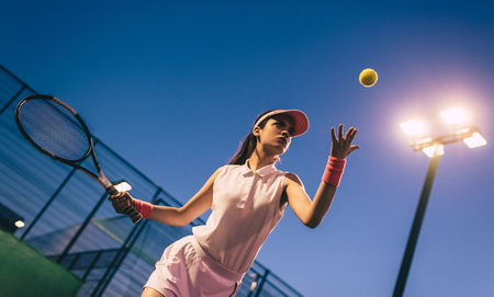 Sport young woman on tennis court in the evening. Female tennis player.の写真素材