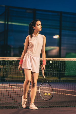 Sport young woman on tennis court in the evening. Female tennis player.の写真素材