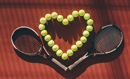 Balls and racket are lying on brown tennis court. I love tennis.の写真素材