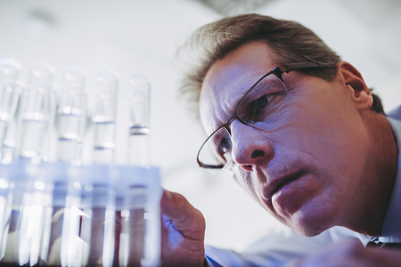Senior experienced scientist is working in laboratory. Doing investigations with test tubes.の写真素材
