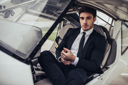 Young handsome businessman is sitting in private plane. Confident and successful man in airport.の写真素材