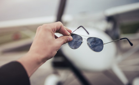 Light propeller airplane on runway. Small private fix-wing plane. Cropped image of man holding...