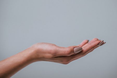 Beautiful woman's hand on grey backgroundの写真素材