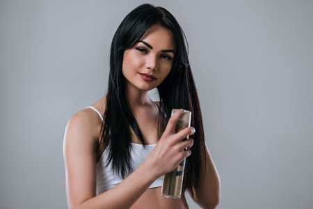 Portrait of attractive young woman with hair spray on grey background. Women careの写真素材
