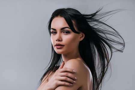 Portrait of attractive young woman with flying hair is looking at the camera on grey background. Women careの写真素材
