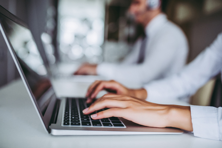 Cropped image of office workers with laptop. Beautiful call center workers are working at office.の写真素材