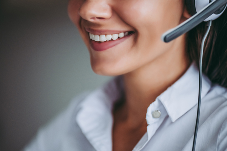 How can I help you? Cropped image of attractive female call center worker in headphones smiling.の写真素材