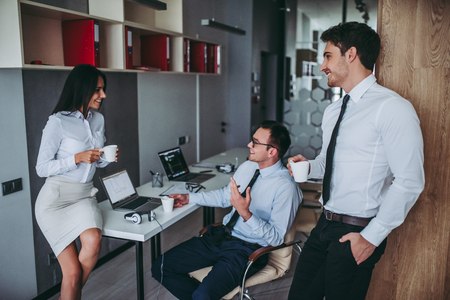 Beautiful young employees are taking coffee break. Workers in modern light office.の写真素材