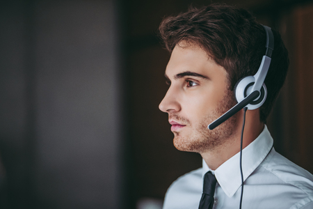 How can I help you?Portrait of handsome male call center worker in headphones is looking to the side.の写真素材