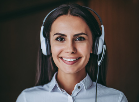 How can I help you?Portrait of attractive female call center worker in headphones is smiling and looking at the camera.の写真素材