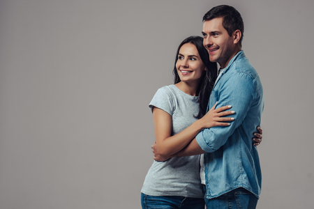Beautiful romantic couple isolated on grey background. Attractive young woman and handsome man are hugging and smiling. Happy Saint Valentine's Day!の写真素材