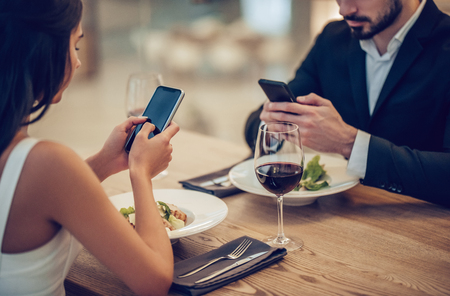 Cropped image of loving couple is spending time together in modern restaurant. Attractive young woman in dress and handsome man in suit are having romantic dinner. Celebrating Saint Valentine's Day.の写真素材