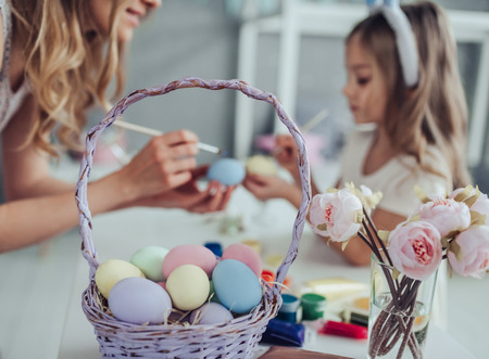 Cropped image of attractive young woman with little cute girl are preparing for Easter celebration. Mom and daughter wearing bunny ears are spending time together before Easter while painting eggs.の写真素材