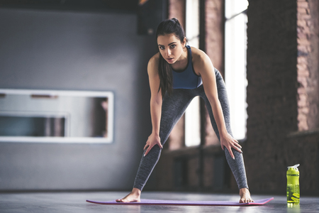Attractive young sport girl is doing yoga in light room. Healthy lifestyle concept.の写真素材