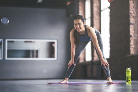 Attractive young sport girl is doing yoga in light room. Healthy lifestyle concept.の写真素材