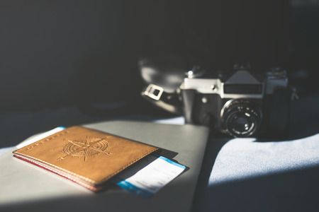 Pasport, tickets, camera and travel bag are lying on sofa in light room. Preparing for travelingの写真素材