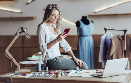 Attractive female fashion designer is working in her workshop. Stylish woman in process of creating new clothes collection.の写真素材