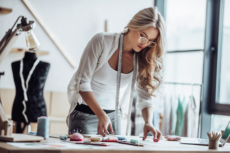 Attractive female fashion designer is working in her workshop. Stylish woman in process of creating new clothes collection.の写真素材