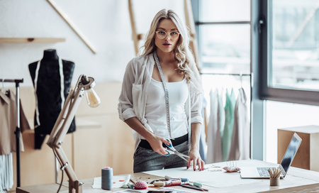 Attractive female fashion designer is working in her workshop. Stylish woman in process of creating new clothes collection.の写真素材