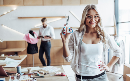 Couple of fashion designers are working in workshop. Attractive young woman and stylish bearded man are in process of creating new clothes collection.の写真素材