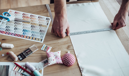 Cropped image of handsome male fashion designer is working in his workshop. Stylish bearded man in...