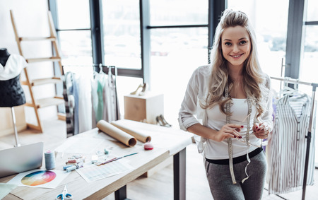 Attractive female fashion designer is working in her workshop. Stylish woman in process of creating new clothes collection.の写真素材