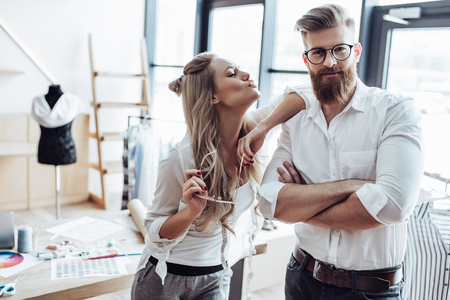 Couple of fashion designers are working in workshop. Attractive young woman and stylish bearded man are in process of creating new clothes collection.の写真素材