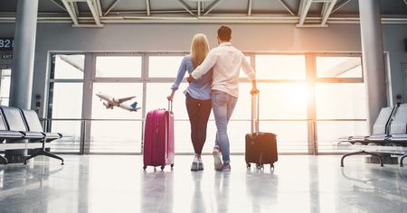 Romantic couple in airport. Attractive young woman and handsome man with suitcases are ready for traveling.の写真素材