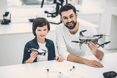 Handsome young man and his cute son are in modern light quadcopter store. Choosing the appropriate droneの写真素材