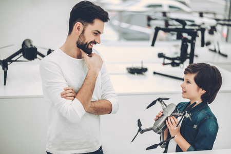 Handsome young man and his cute son are in modern light quadcopter store. Choosing the appropriate droneの写真素材