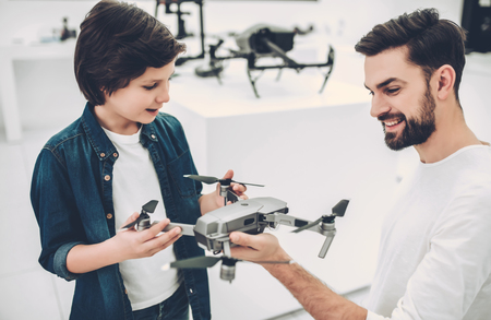 Handsome young man and his cute son are in modern light quadcopter store. Choosing the appropriate droneの写真素材