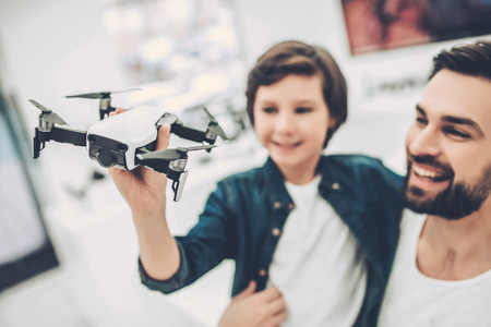 Handsome young man and his cute son are in modern light quadcopter store. Choosing the appropriate droneの写真素材