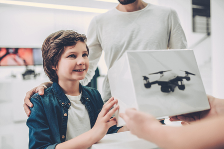 Cropped image of handsome young man and his cute son are in modern light quadcopter store. Buying the appropriate droneの写真素材