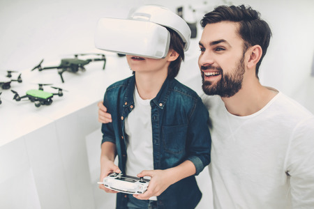 Handsome young man and his cute son are in modern light quadcopter store. Little boy wearing glasses of virtual reality.の写真素材