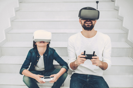 Handsome young man and his cute son are in modern light quadcopter store wearing glasses of virtual reality.の写真素材