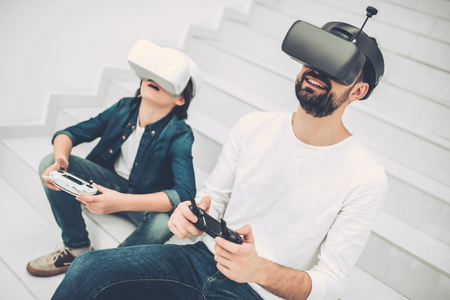 Handsome young man and his cute son are in modern light quadcopter store wearing glasses of virtual reality.の写真素材