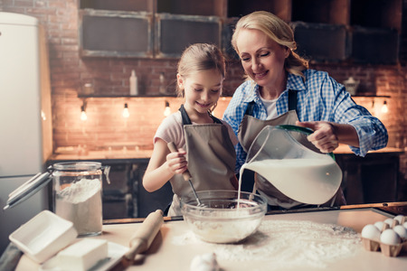 Grandmother and granddaughter are cooking on kitchen. Making tasty baking together.の写真素材